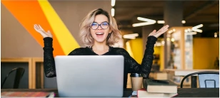 mulher na frente do notebook sorrindo e com os braços abertos